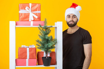 年轻的积极的男人。胡子圣诞老人老人他站展位礼物圣诞节树黄色的背景概念祝贺礼物折扣圣诞节一年