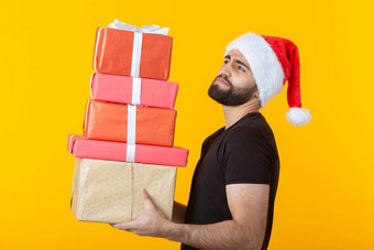 不满的年轻的男人。胡子圣诞老人老人他持有礼物盒子摆姿势黄色的背景概念礼物圣诞节一年
