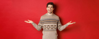 肖像快乐好看的男人。庆祝一年假期穿圣诞节毛衣传播手横盘整理微笑持有复制空间站红色的背景