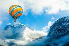 色彩斑斓的热空气气球飞行冰雪覆盖山