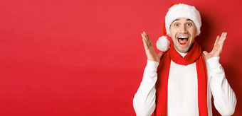 概念圣诞节冬天假期庆祝活动图像英俊的男人。惊讶一年促销提供微笑惊讶站红色的背景
