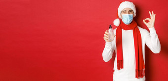 概念科维德圣诞节假期流感大流行快乐的男人。庆祝一年医疗面具圣诞老人他推荐手洗手液显示标志眨眼