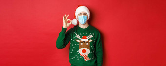 概念一年科维德社会距离快乐的男人。医疗面具圣诞老人他显示标志推荐好站红色的背景