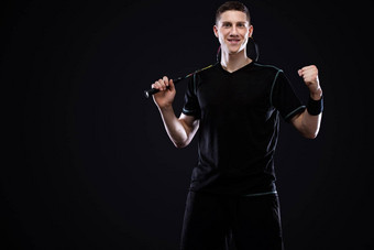 羽毛球球员运动服装球拍羽毛球黑色的背景男人。庆祝胜利黑暗背景