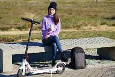 女学生电踏板车采取咖啡打破坐着板凳上大学