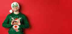 图像快乐微笑男人。聚会，派对眼镜圣诞老人他愚弄有趣的圣诞节毛衣庆祝冬天假期站红色的背景