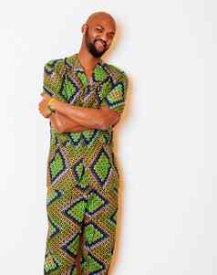 肖像年轻的英俊的非洲男人。穿明亮的绿色国家服装微笑手势娱乐的东西