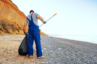 男人。志愿者收集垃圾海滩达到扩展器坚持