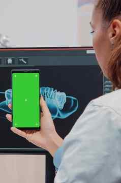 牙医垂直持有智能手机绿色屏幕
