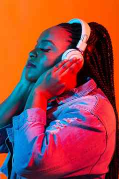 年轻的非裔美国人女人听音乐耳机霓虹灯光女肖像概念人类情绪面部表达式假期周末爱好