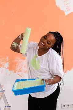 美丽的非洲美国女孩绘画墙油漆辊肖像年轻的美丽的女人绘画墙公寓重新装饰改造概念