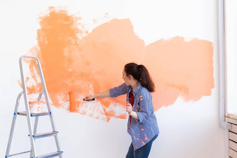 快乐微笑女人绘画室内墙房子重新装饰改造公寓修复点心概念