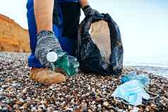 手男人。志愿者抓住塑料垃圾浪费袋清洁海滩