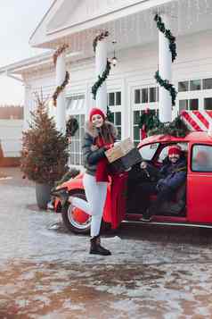 年轻的夫妇购买圣诞节礼物家庭首页红色的车