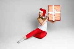 有趣的女人圣诞节他坐在大红色的盒子听到内部图片孤立的白色背景