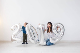 一年庆祝活动假期概念妈妈。儿子坐着标志使银气球一年白色房间背景