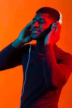 霓虹灯肖像年轻的非洲男人。听音乐耳机