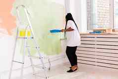 修复公寓快乐年轻的女人油漆墙油漆