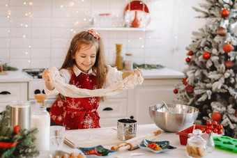 女孩红色的围裙一年的厨房准备面团圣诞节饼干