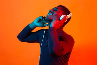 非洲美国年轻的男人。听音乐在线跳舞唱歌耳机霓虹灯光音乐技术概念