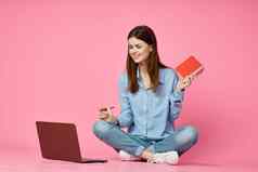 快乐的女人移动PC坐着地板上粉红色的背景互联网技术