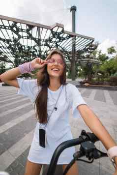 年轻的美丽的女人电踏板车生态运输