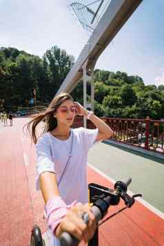 年轻的美丽的女人电踏板车生态运输