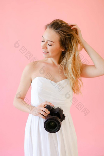 年轻的可爱的女摄影师相机粉红色的单声道的背景
