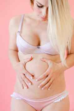 高加索人怀孕了女人持有肚子粉红色的单声道的背景