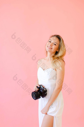 年轻的微笑女<strong>摄影</strong>师相机粉红色的单声道的背景