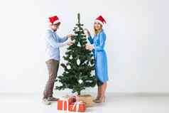 假期节日概念年轻的家庭夫妇圣诞老人帽子装修圣诞节树