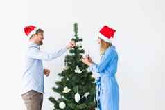 假期节日概念年轻的家庭夫妇圣诞老人帽子装修圣诞节树