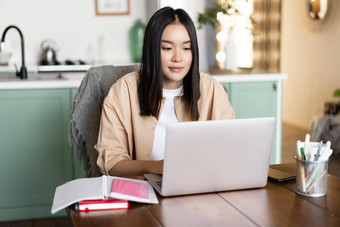 亚洲女孩研究首页距离教育概念女学生学习移动PC年轻的女人工作远程坐着厨房书电脑