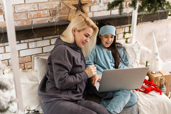 高加索人女人女儿圣诞节视频闲谈，聊天朋友家庭移动PC屏幕坐着沙发首页拥抱社会距离科维德流感大流行圣诞节