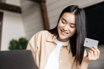 微笑亚洲女孩购买在线持有信贷卡手购物移动PC首页生活房间