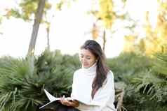 中国人女孩坐着树桩公园阅读论文