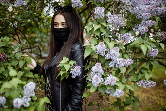 女孩医疗面具背景开花淡紫色公园黑色的面具冠状病毒保护春天过敏