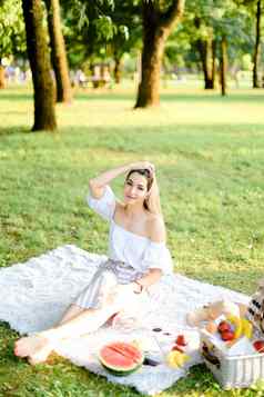 年轻的欧洲女人野餐格子坐着公园水果