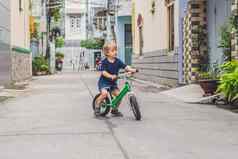 活跃的金发碧眼的孩子男孩开车自行车街城市蹒跚学步的孩子做梦有趣的温暖的夏天一天在户外游戏孩子们平衡自行车概念