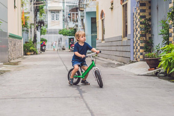 活跃的金发碧眼的孩子男孩开车自行车街城市蹒跚学步的孩子做梦有趣的温暖的夏天一天在户外游戏孩子们平衡自行车概念
