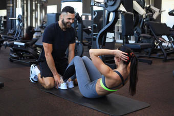 教练帮助年轻的女人腹部练习健身房