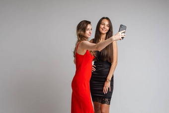 漂亮的年轻的女孩博客穿时尚的礼服使<strong>自拍摄</strong>影电话摆姿势灰色的工作室背景
