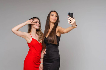 漂亮的年轻的女孩博客穿时尚的礼服使自拍摄影电话摆姿势灰色的工作室背景