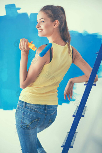 快乐美丽的年轻的女人墙绘画站梯