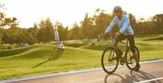 专业路自行车赛车手培训在户外年轻的运动男人。运动服装保护头盔站自行车路公园准备好了骑