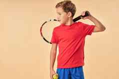 可爱的男孩网球球员站光橙色背景