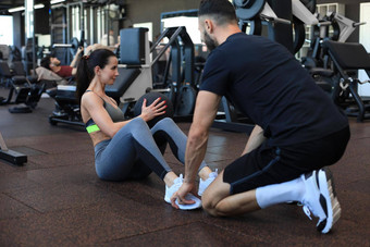教练帮助年轻的女人腹部练习健身房