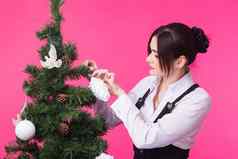 人假期圣诞节概念女人装修圣诞节树粉红色的背景