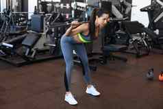 肌肉发达的女人工作健身房练习杠铃肱二头肌