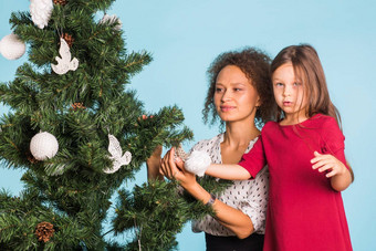 混合比赛妈妈女儿圣诞节树蓝色的背景